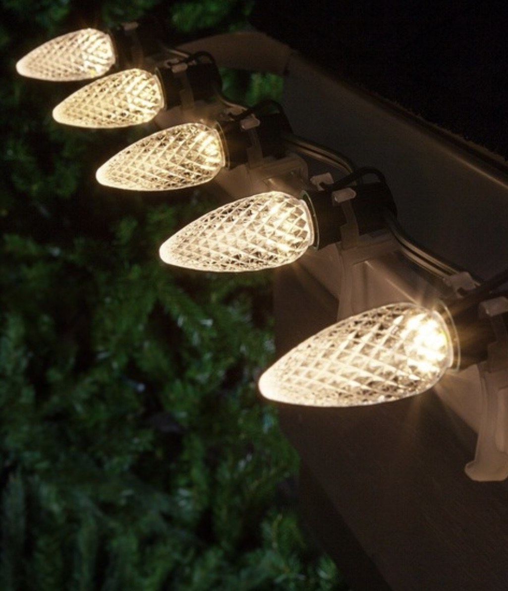 Close-up of illuminated C9 Christmas light bulbs mounted along a roofline